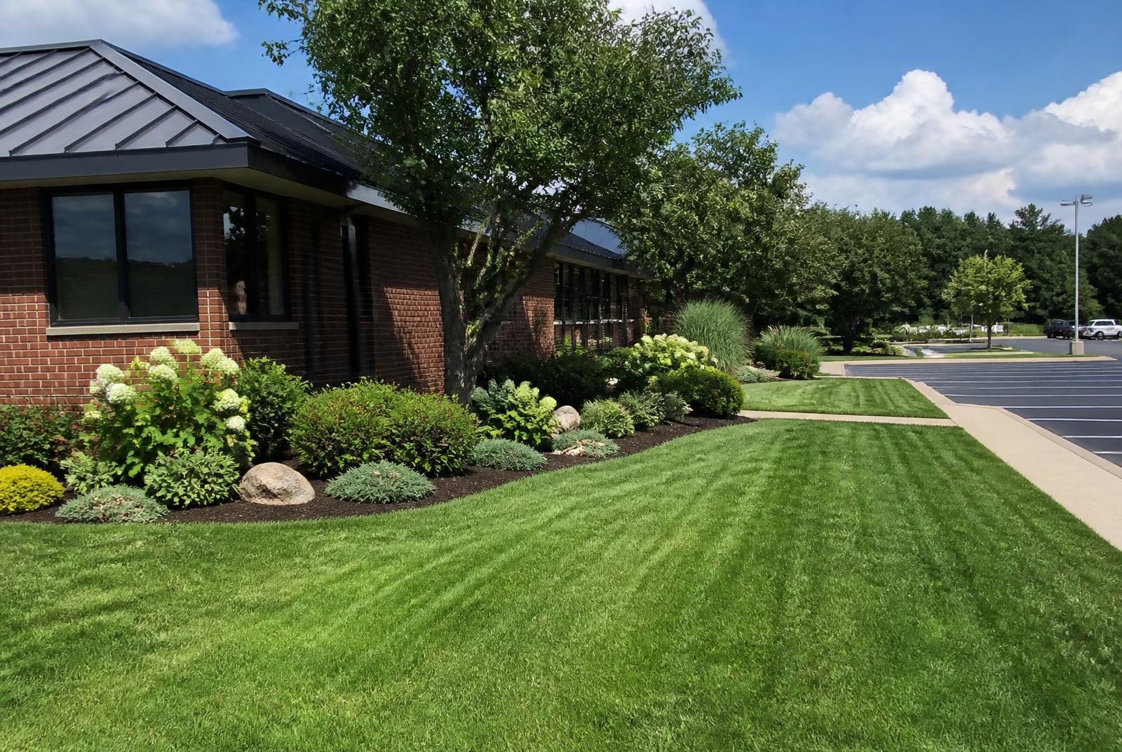 Neatly maintained lawn and shrub beds in front of a small brick commercial building