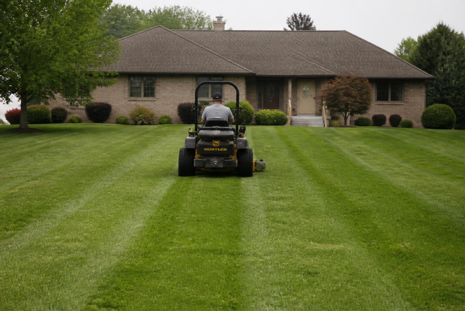 Zero-turn mower cutting clean stripes into a residential lawn